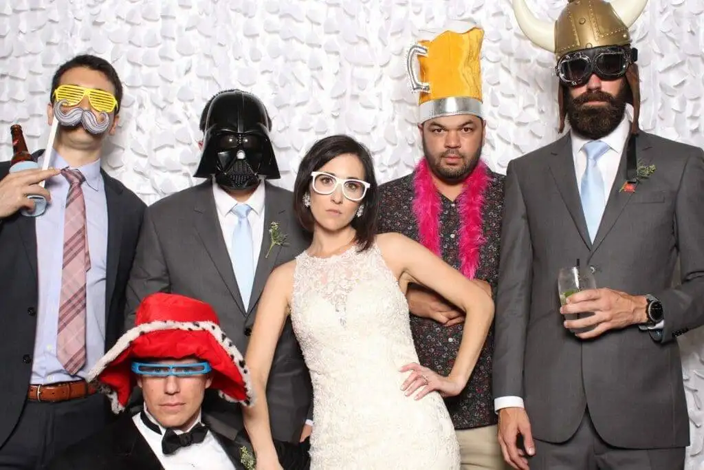 Several Wedding guests posing with props in wedding photo booth