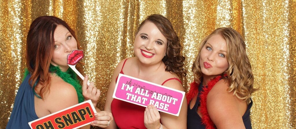 Three attractive women posing in a wedding photo booth